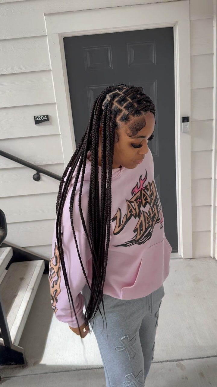 Person displaying long, dark medium box braids beside a white-sided doorway