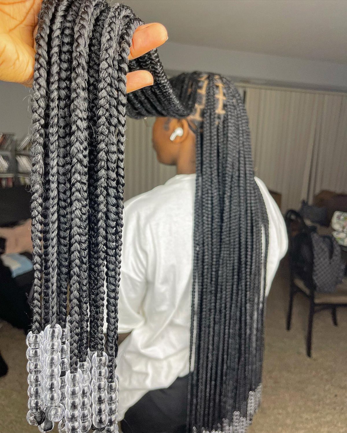 Long black box braids ending in clear beads, with person seated indoors