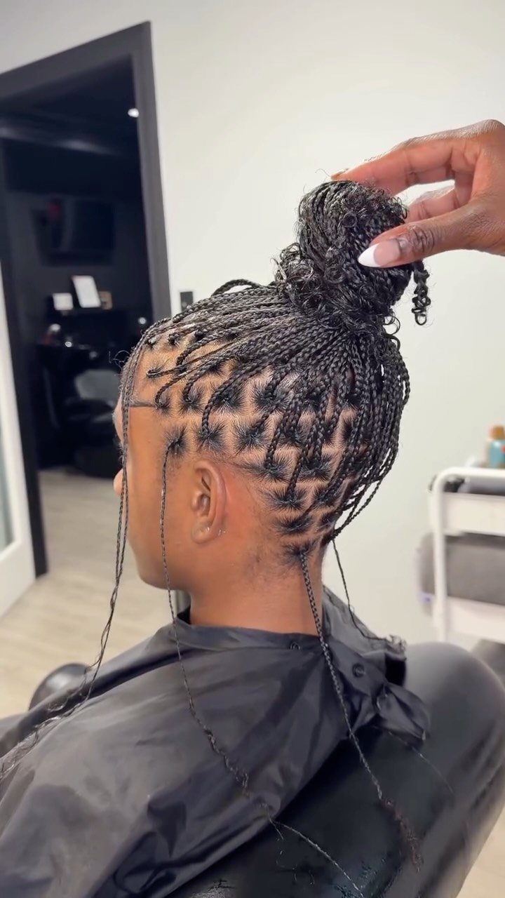 Black box braids gathered into a crown bun in a salon chair
