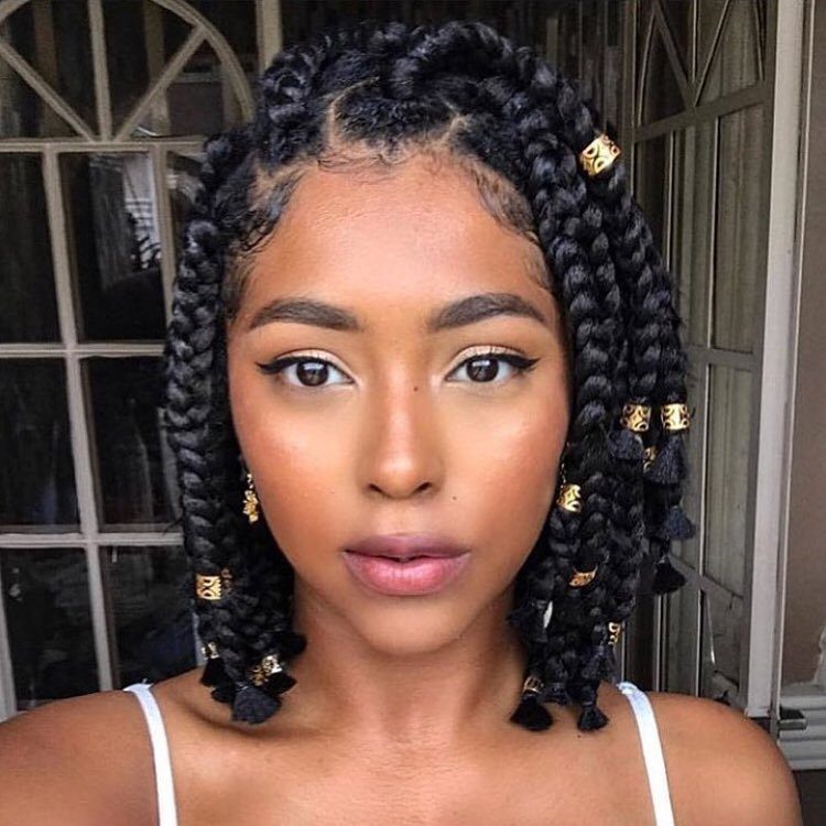 Woman wearing shoulder-length black box braids decorated with gold hair cuffs