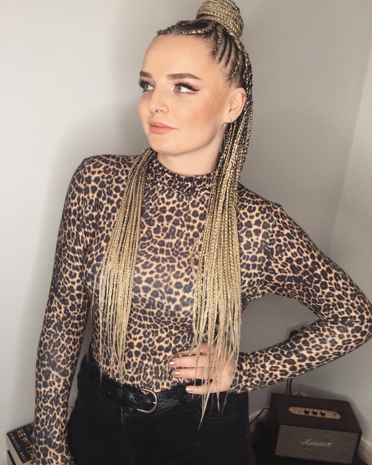 Woman wearing blonde-highlighted braids gathered into a high bun