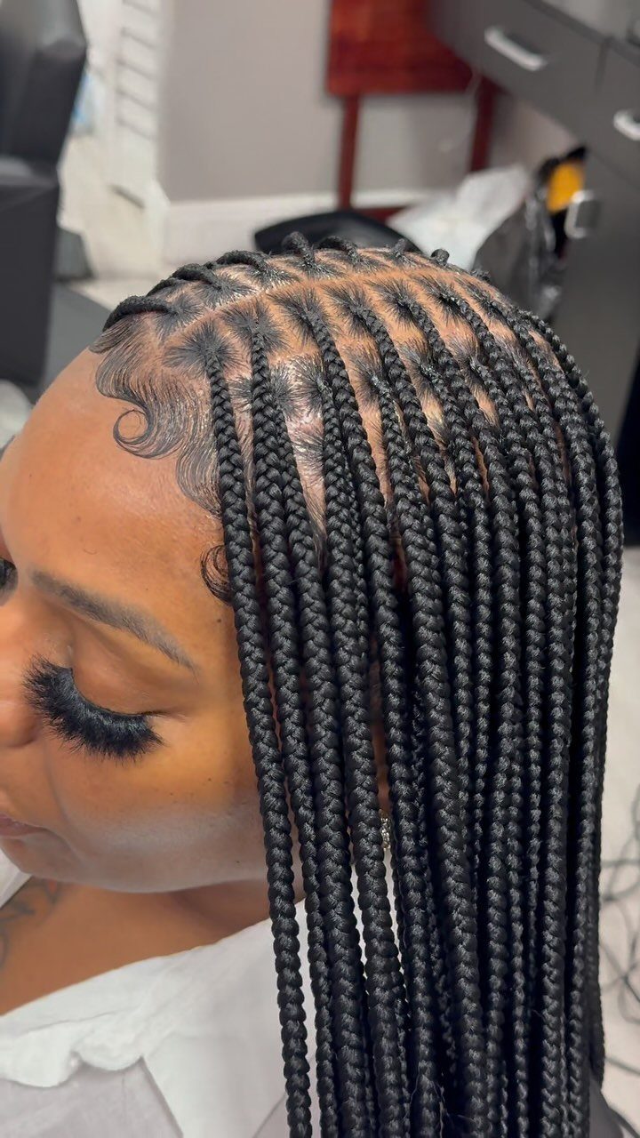 Long black box braids emerge from neat square scalp sections on a masked person