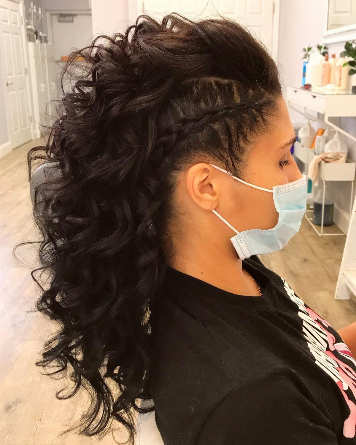 Braided faux hawk with voluminous dark curls worn by a masked person