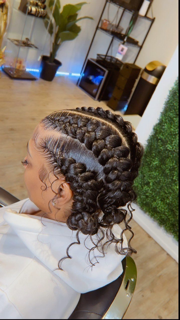 Curved scalp braids gathered into curled ends on a seated salon client
