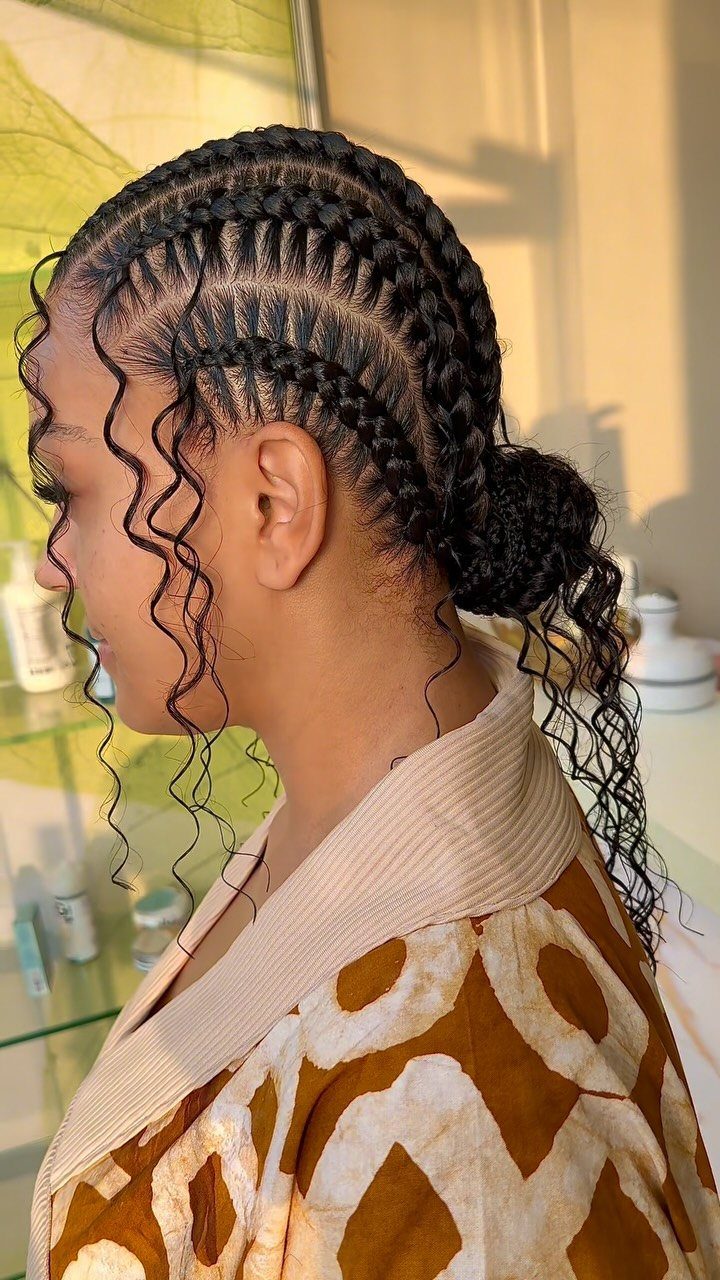 Small side cornrows blend into loose curls around the face and nape