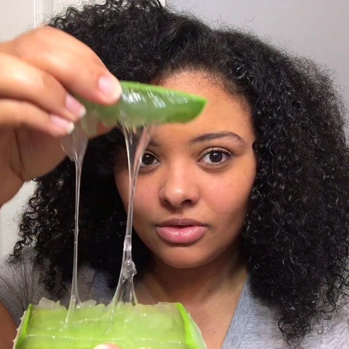 Woman holds a cut aloe leaf above a container of dripping gel