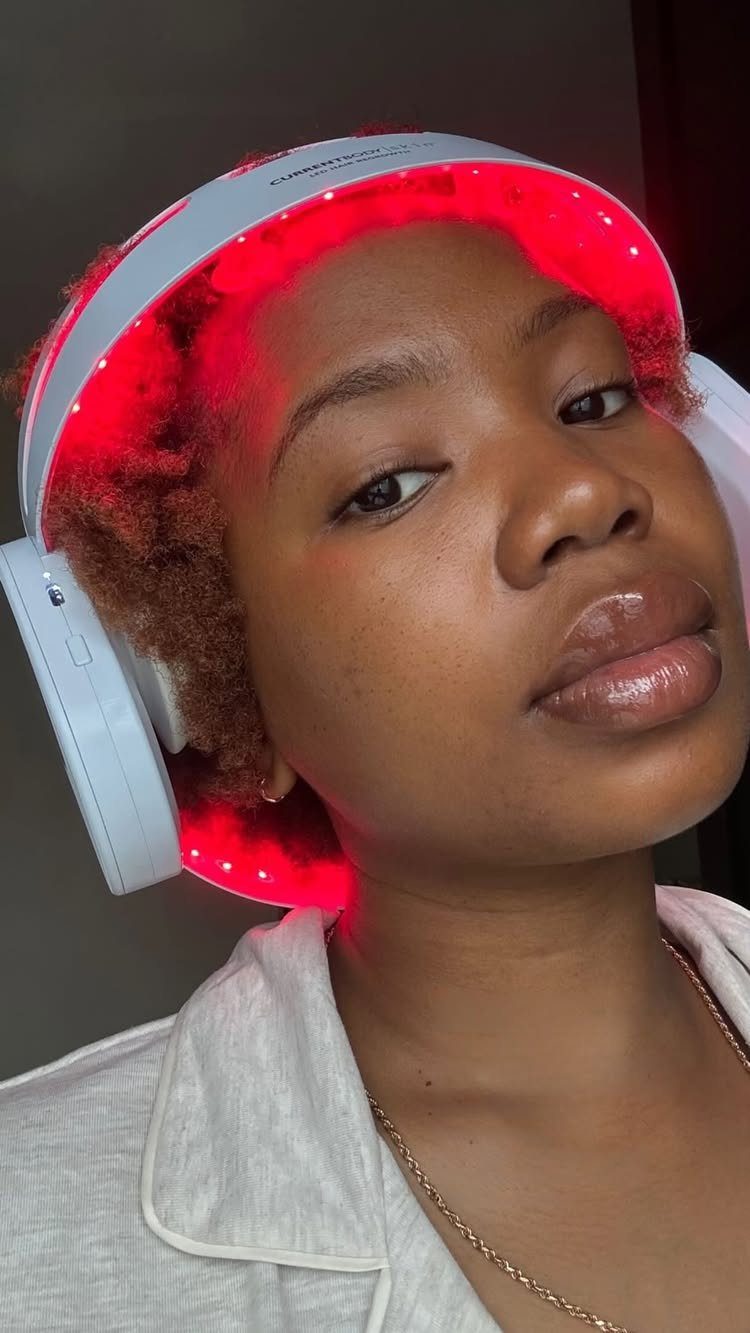Red light therapy device glowing around a person's scalp