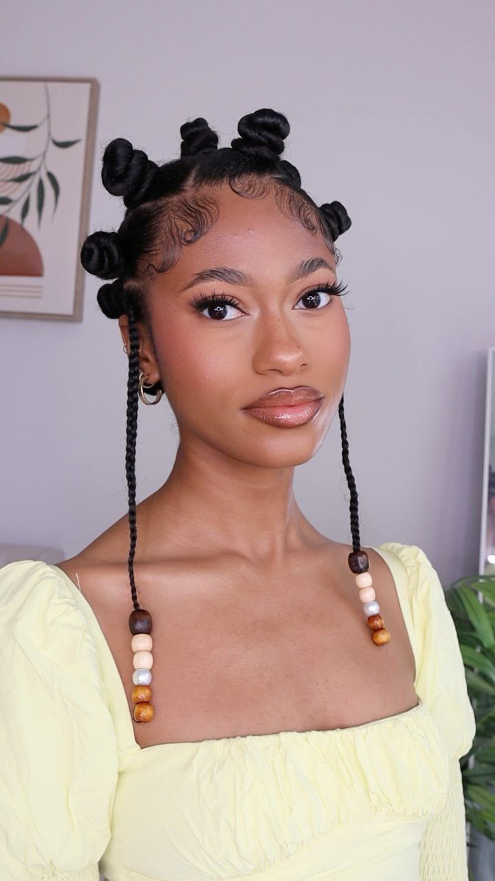 Woman wearing multiple Bantu knots with long beaded braided tendrils indoors