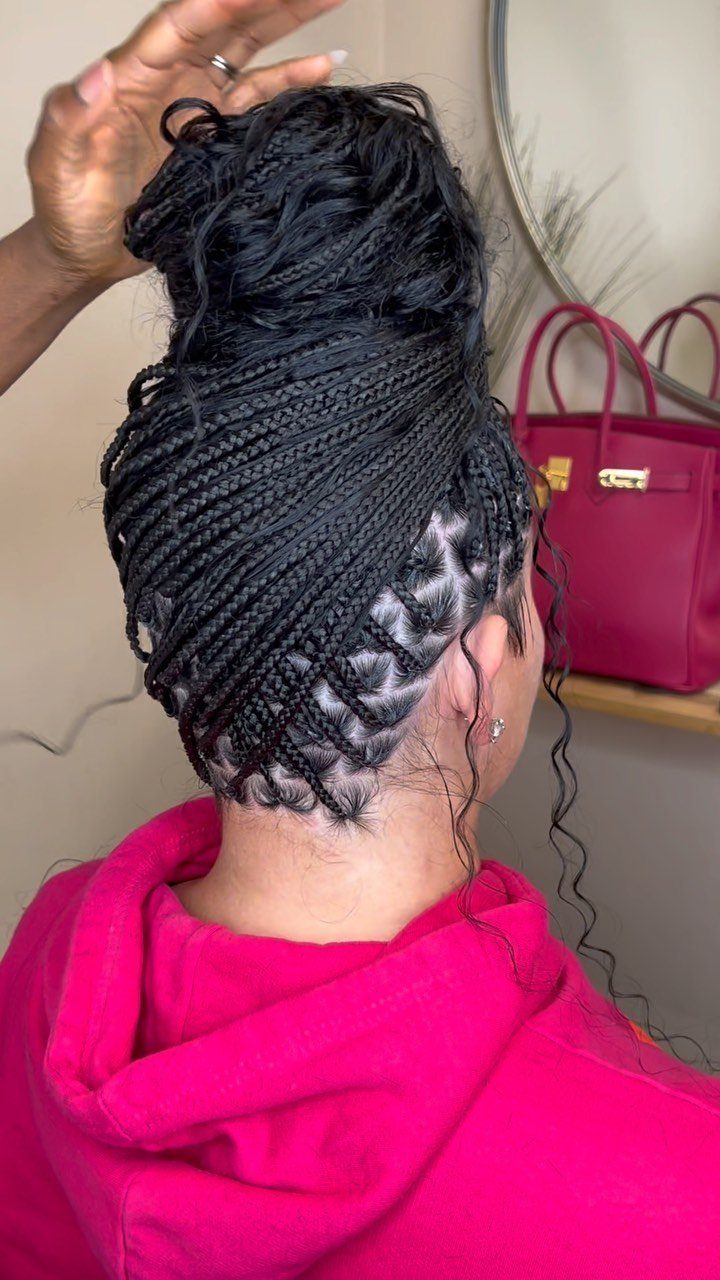 Box braids gathered into a high bun with loose curls at the nape