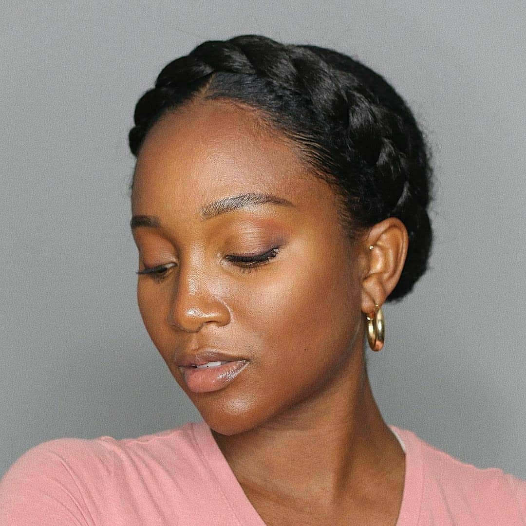 Woman wearing a glossy black crown braid with gold hoop earrings