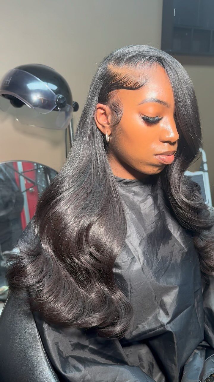 Woman showing long, glossy curls styled with a deep side part in a salon