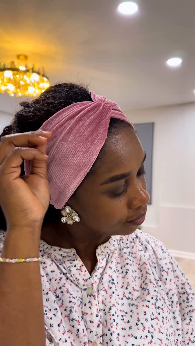 Woman adjusting an oversized mauve headband over natural textured hair
