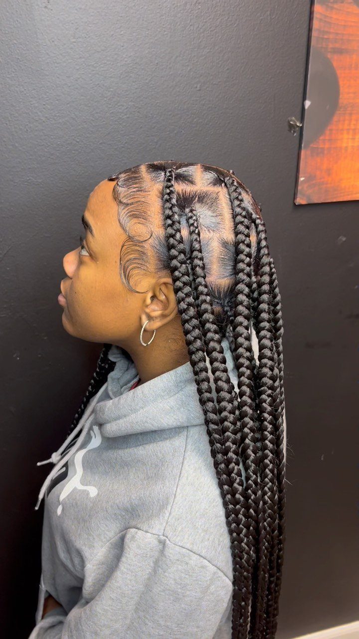Long box braids on a person in side profile against a dark wall