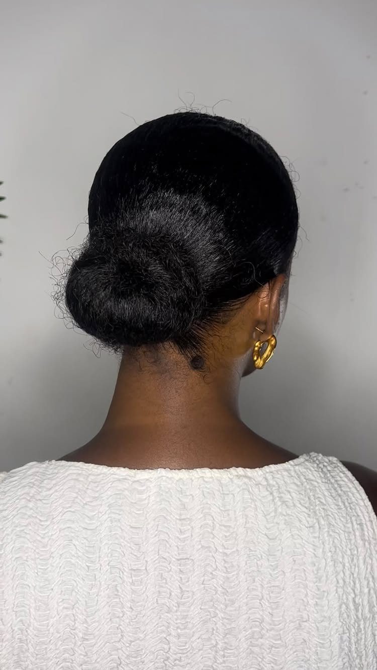 Dark hair gathered into a smooth low bun at the nape