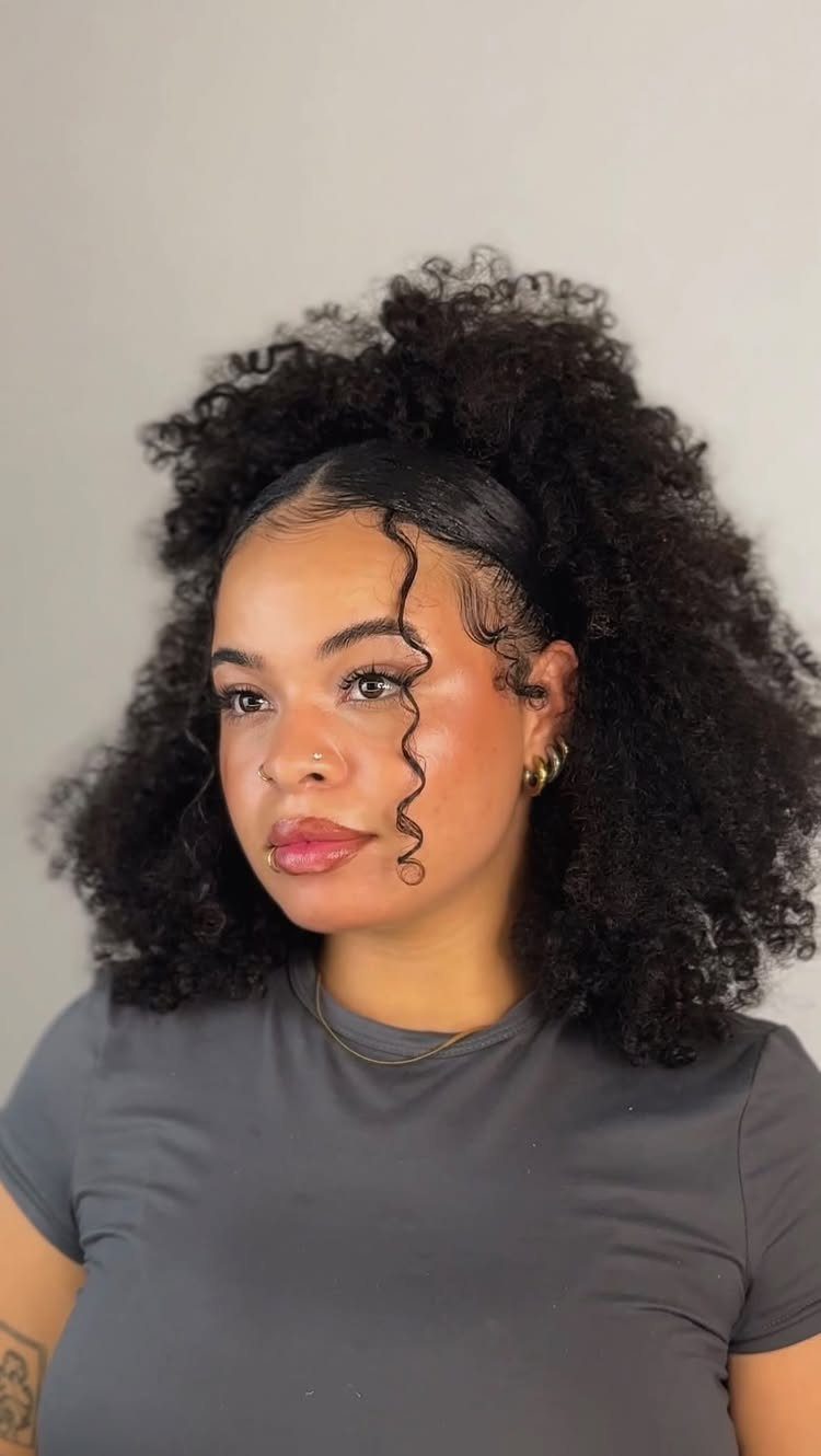 Woman wearing voluminous natural curls gathered high in a loose pineapple puff