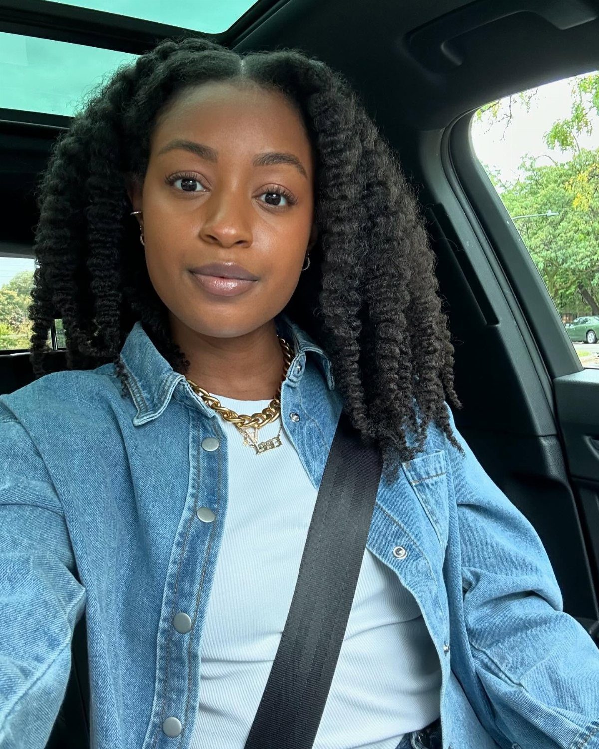Woman with long, voluminous natural curls seated in a car