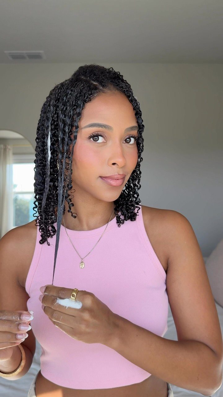 Woman showcasing defined natural curls in a pink sleeveless top indoors