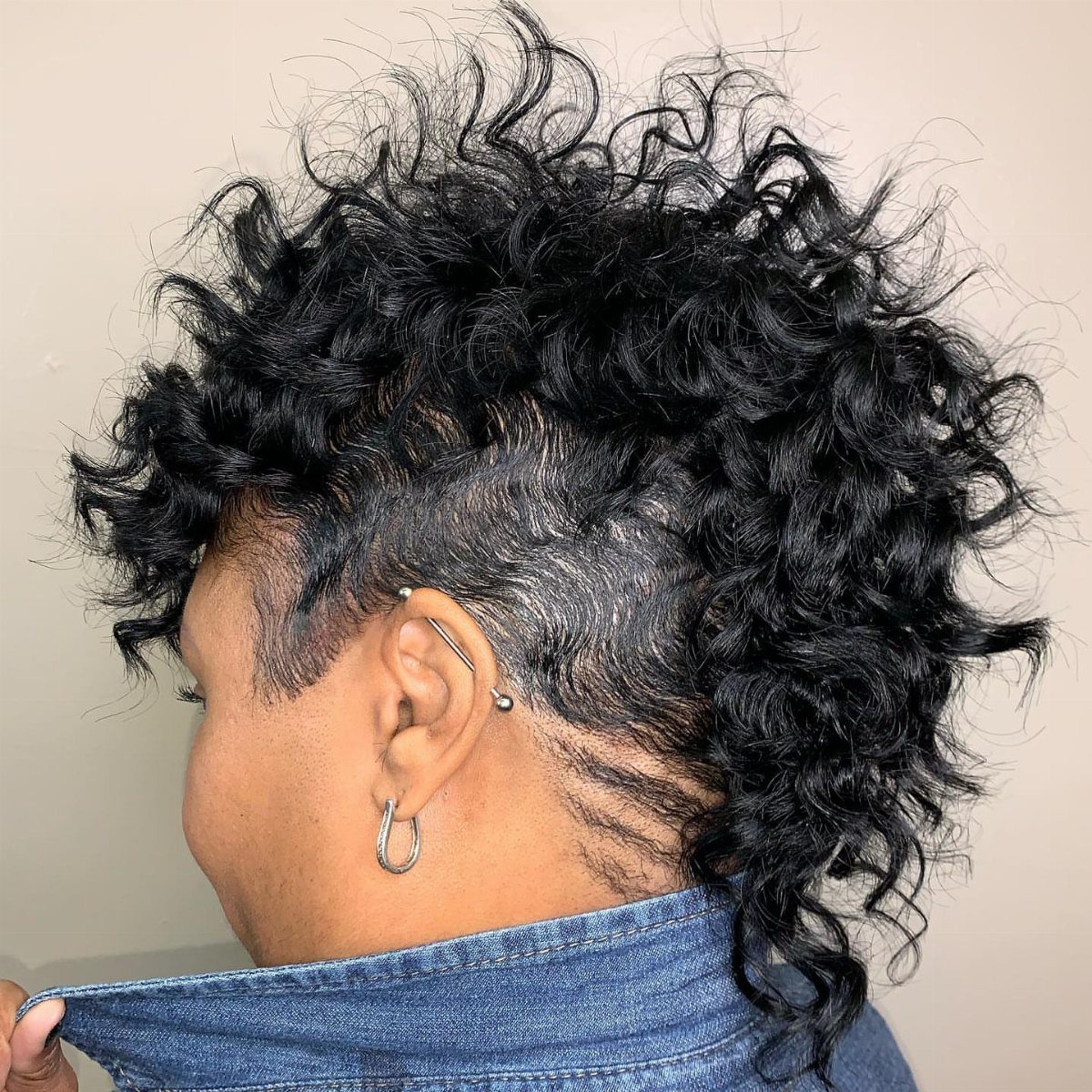Curly mohawk with voluminous black curls and closely cropped sides