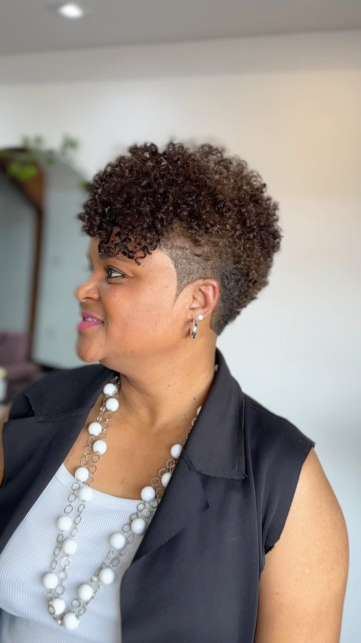 Woman showing a short natural curly pixie with closely tapered sides