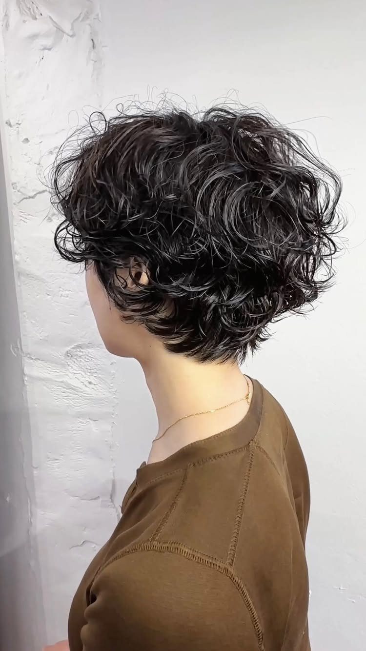 Side profile showing short layered dark curls with shaggy volume at the nape
