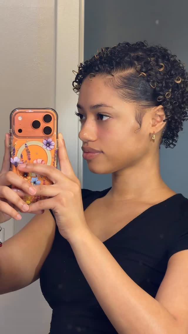 Woman showing short curly hair with a deep side part tucked behind her ear