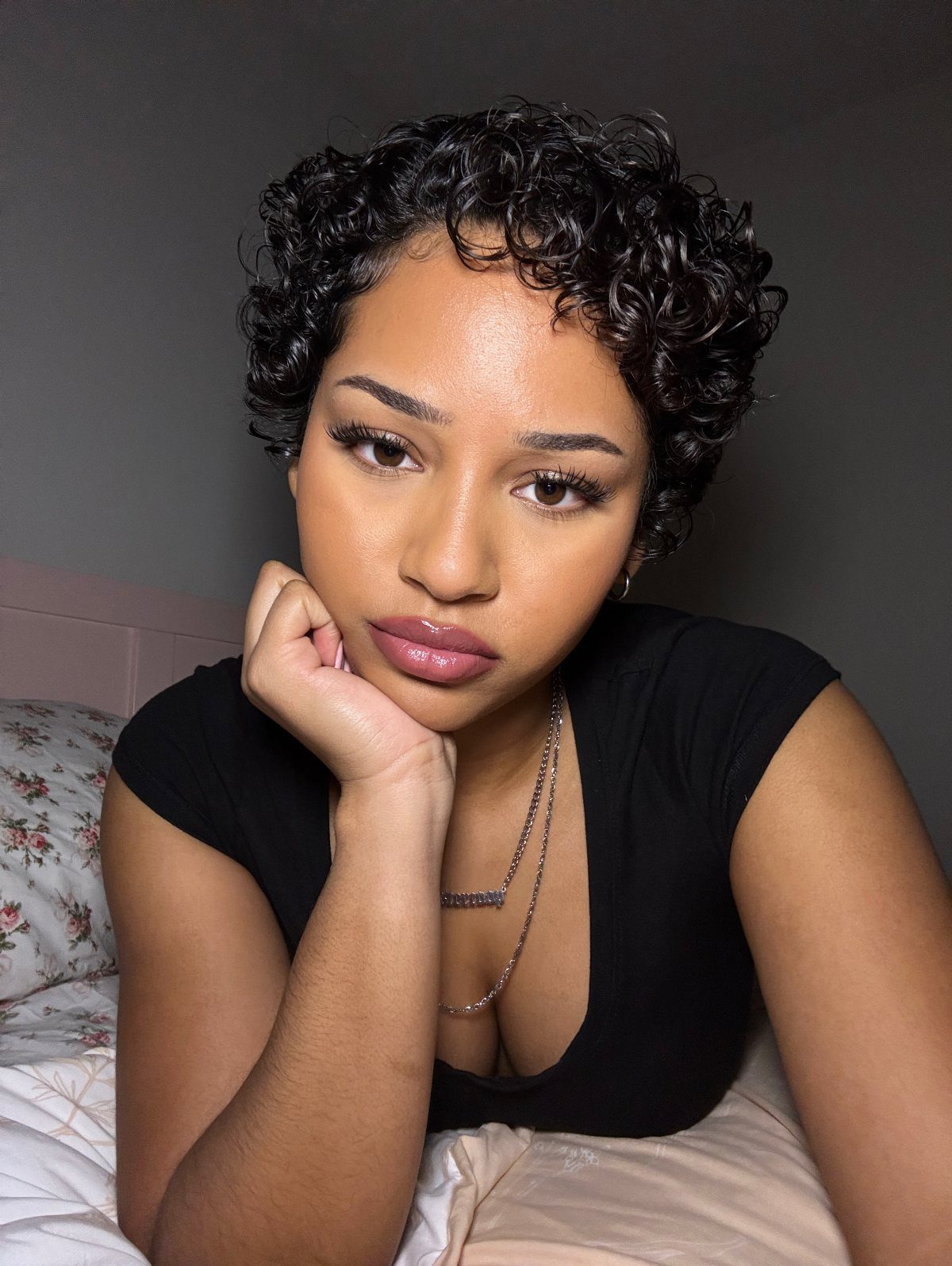 Woman posing with a rounded crop of short natural dark curls indoors