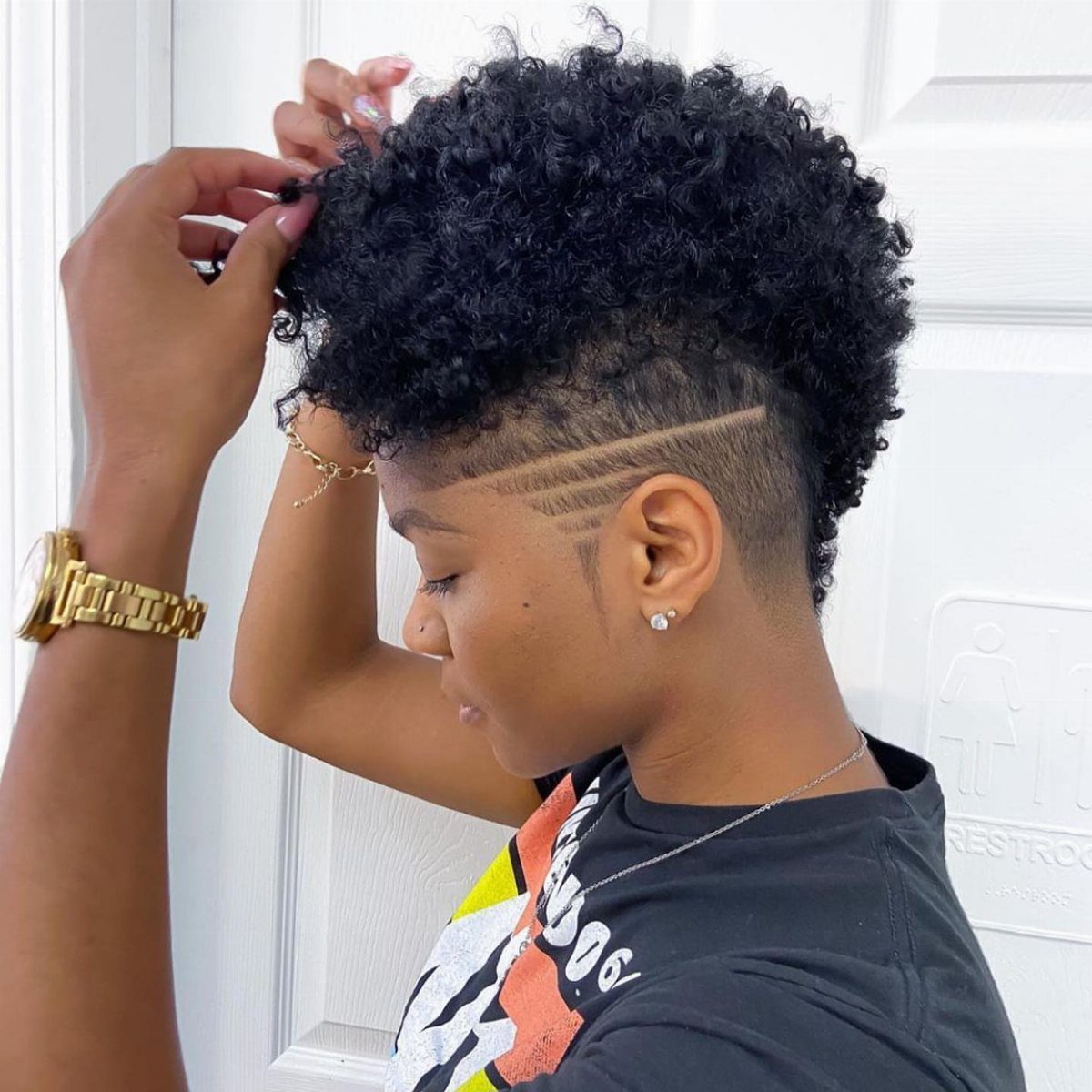 Curly fauxhawk with full black curls, shaved sides, and curved razor lines