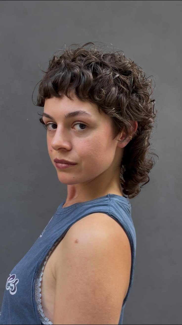 Curly mullet with short bangs and sides and longer curls at the back