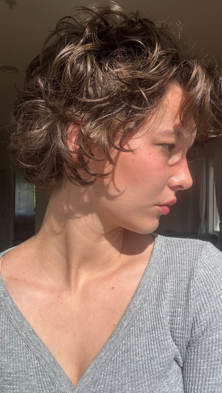 Short curly pixie bob with tousled layers framing the person's profile