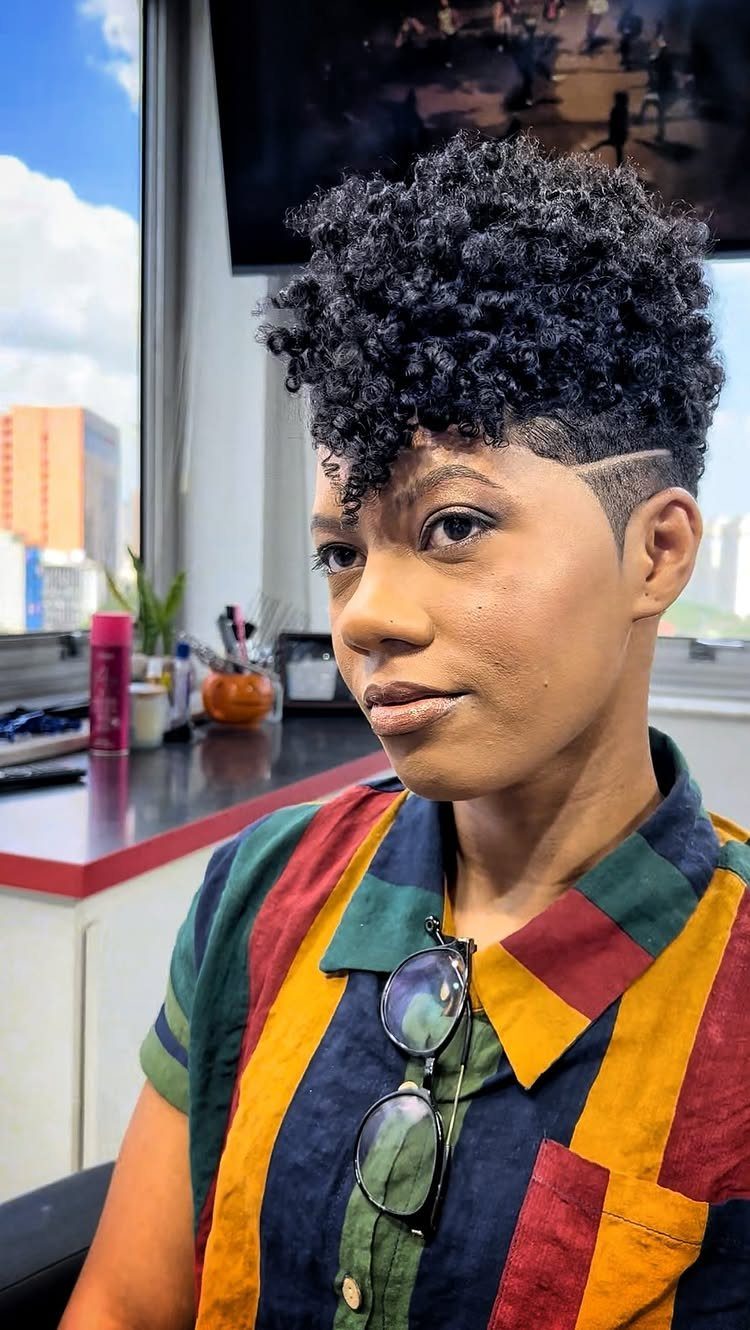 Tall black curls styled over closely cropped sides in a salon