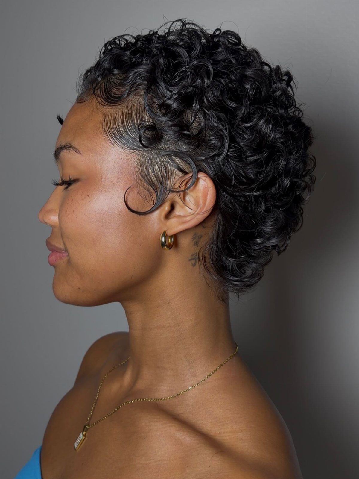Short defined ringlet crop on a woman shown in side profile