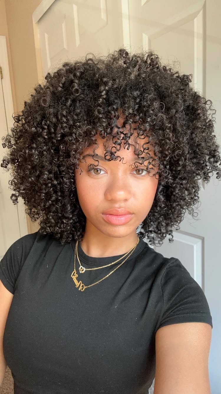 Woman displaying voluminous, defined natural curls with a simple black shirt