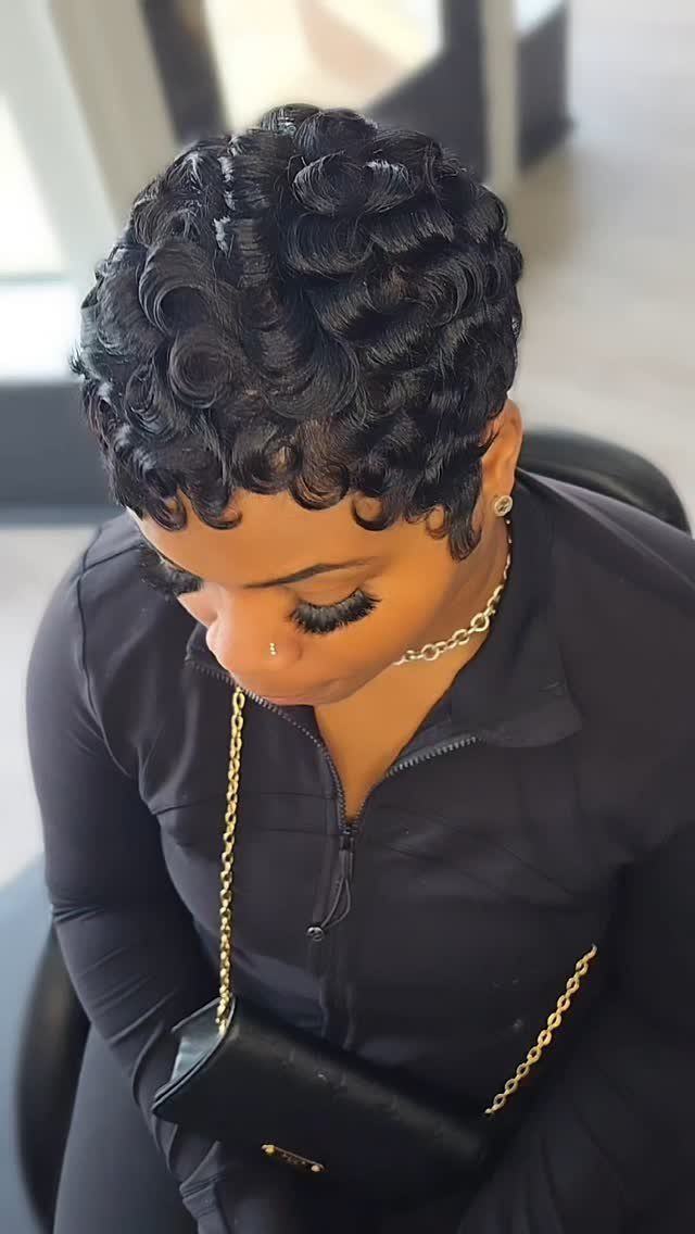Short dark curls styled into sculpted finger waves on a woman