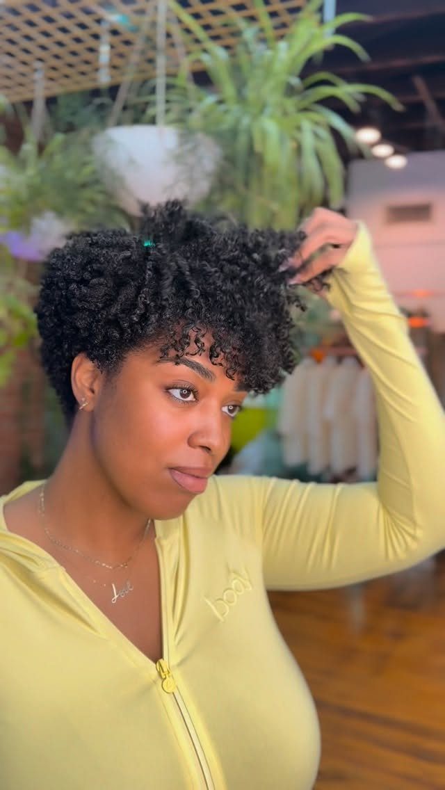 Woman with short voluminous curly hair adjusting her hairstyle indoors