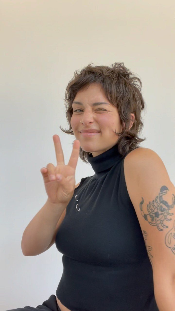 Short brown wavy shag with a forehead fringe on a person posing