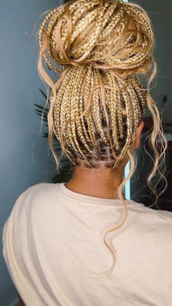 Small blonde box braids gathered into a high bun with loose curly strands
