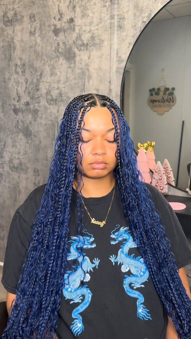 Woman with long, narrow blue-and-black box braids poses in front of a mirror