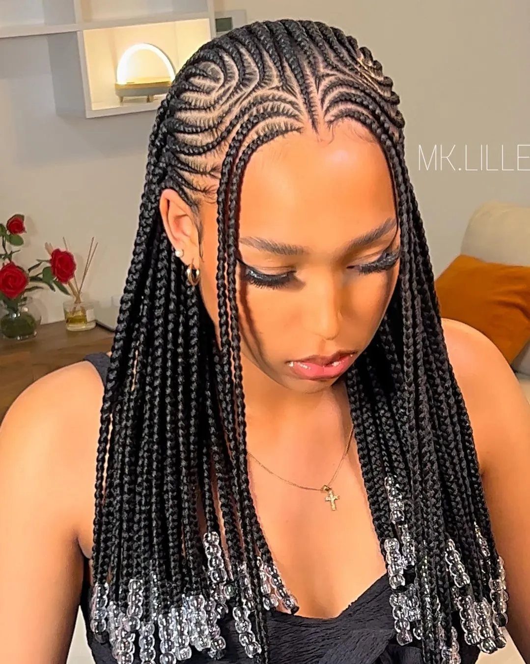 Woman showing long black box braids finished with clear beads at the ends