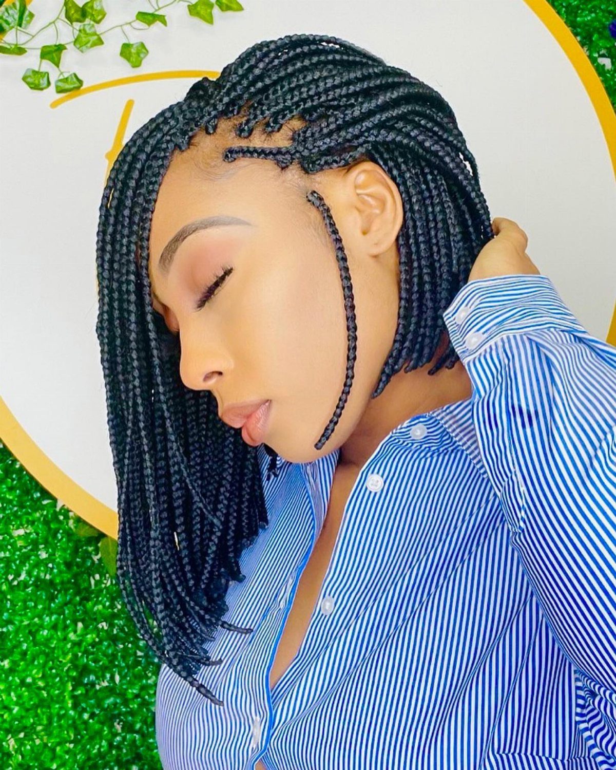 Woman with small black box braids wearing a blue-and-white striped shirt