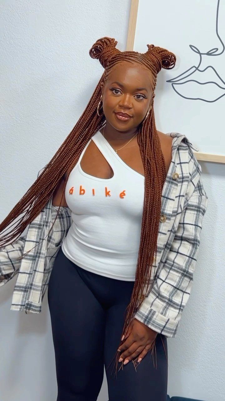 Woman showing long reddish-brown braids, cornrowed crown, and two top buns