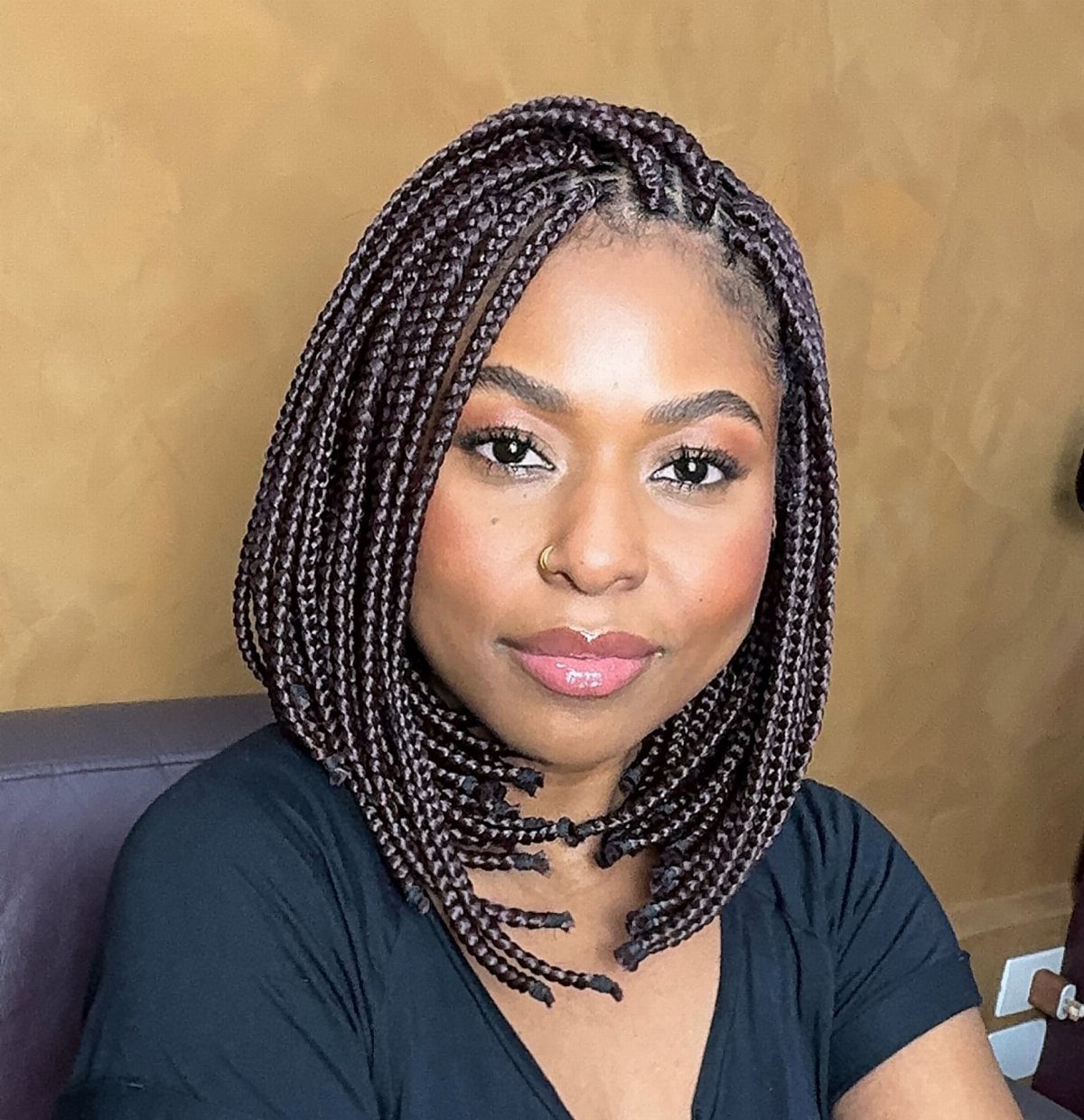 Woman wearing shoulder-length dark box braids with a center part