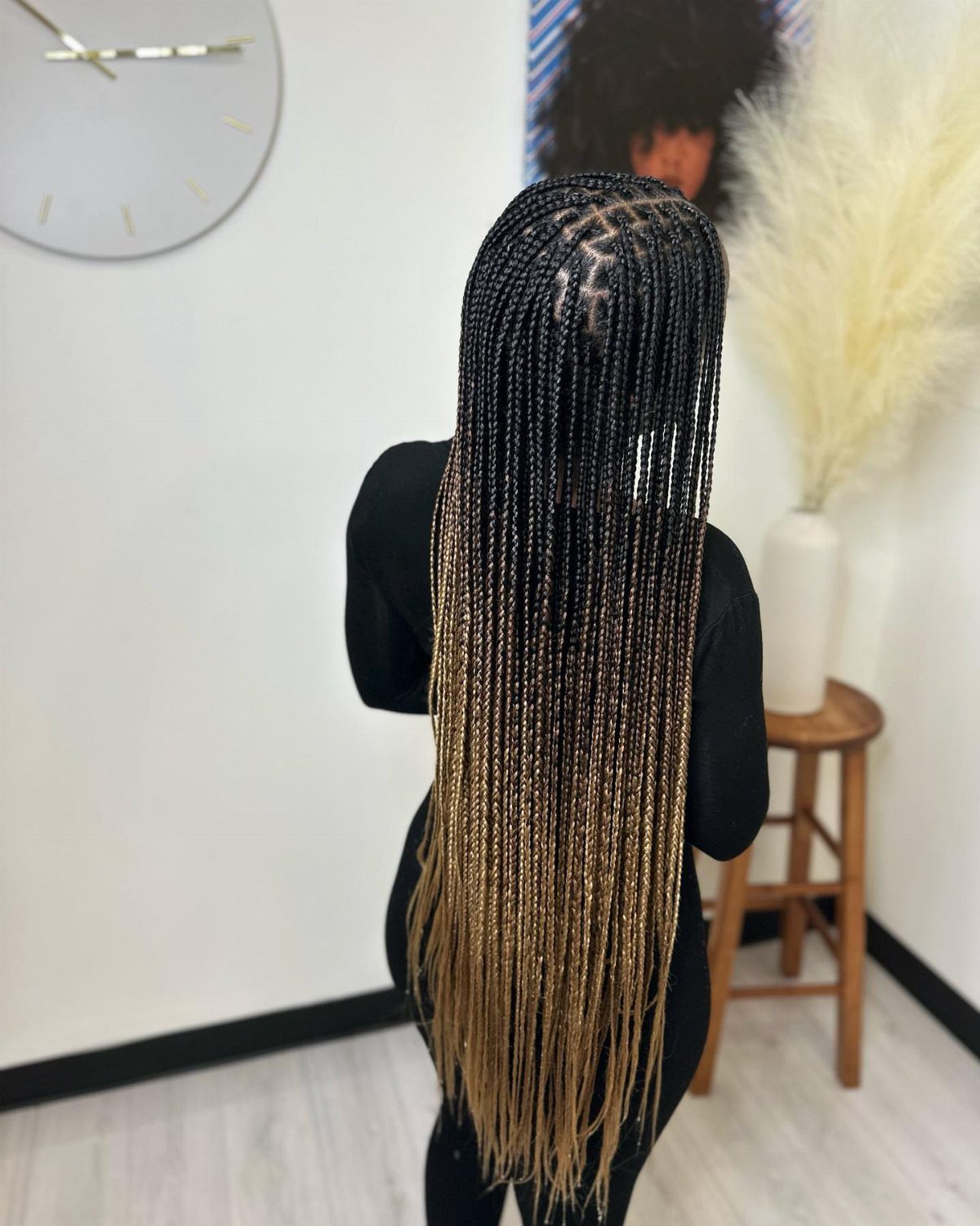 Long box braids fade from black roots to blonde ends down the person's back