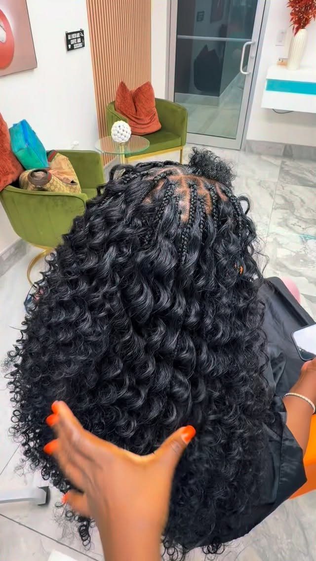 Small black braids with loose curls cascading down a seated person's back
