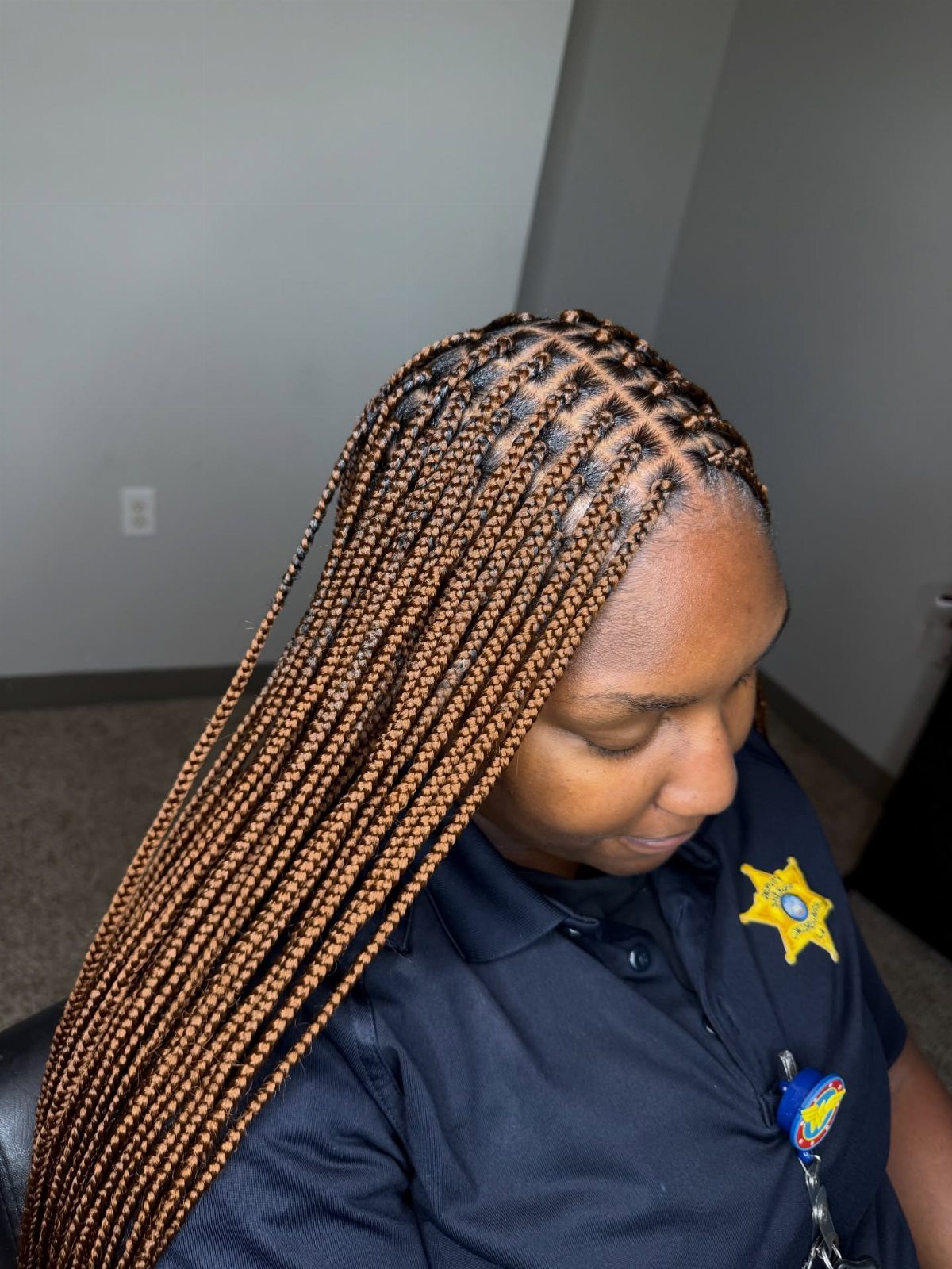 Small highlighted box braids hang over one shoulder as the wearer looks down