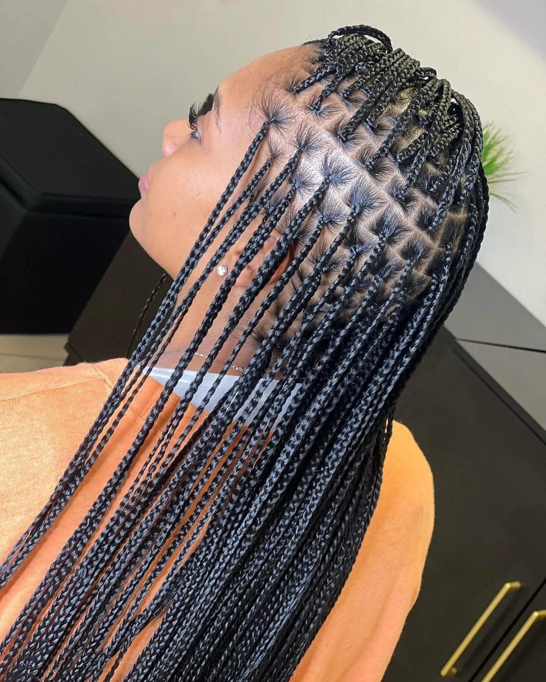 Long, thin black knotless box braids fall over a person’s shoulder