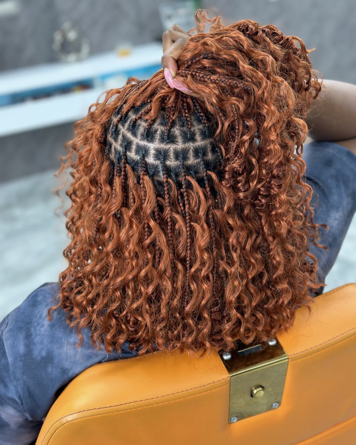 Copper-brown boho bob braids with curly ends shown from behind in a salon chair