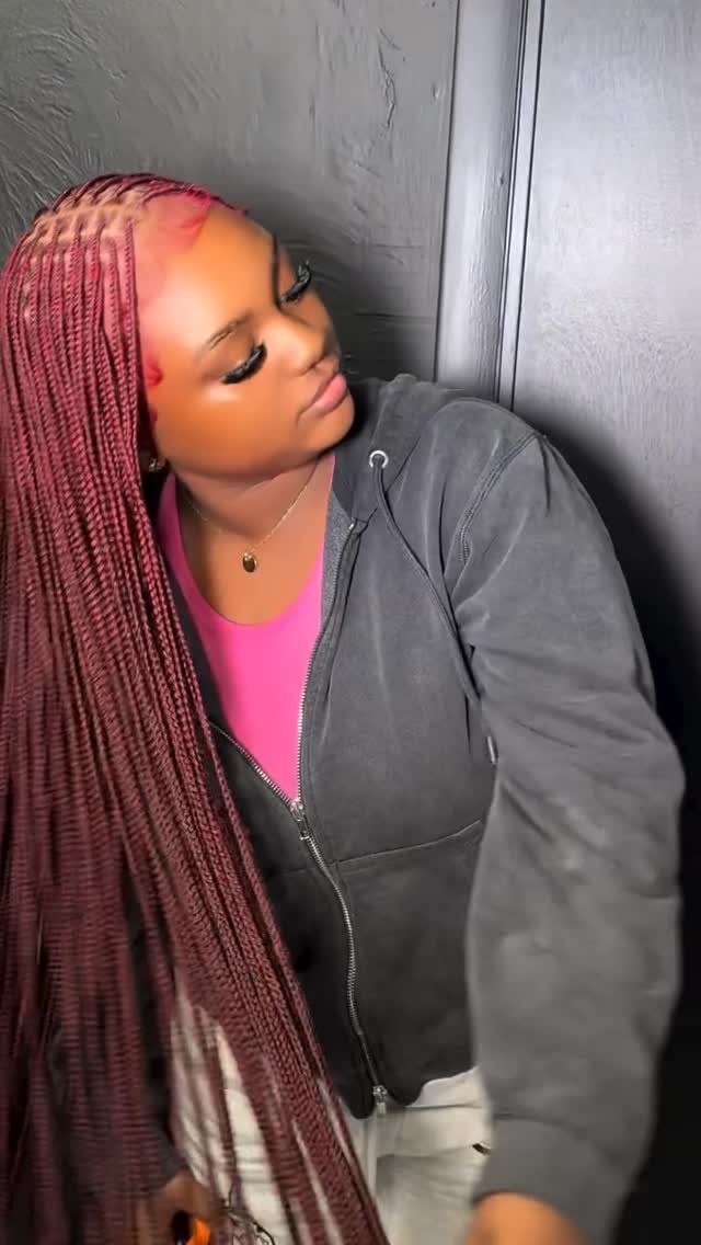 Woman wearing very long, fine burgundy braids with a gray jacket