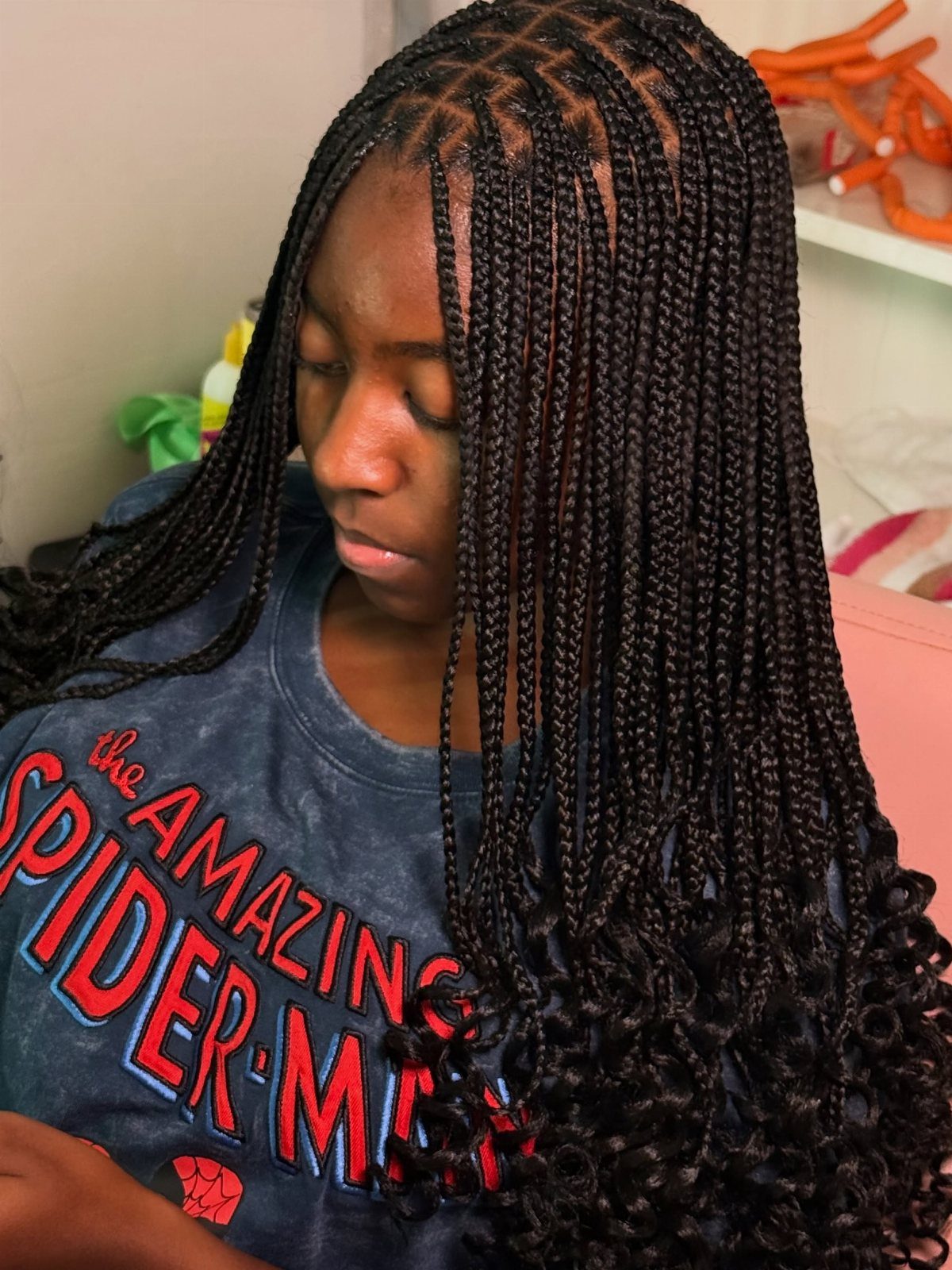 Woman wearing long layered small black knotless braids with curled ends