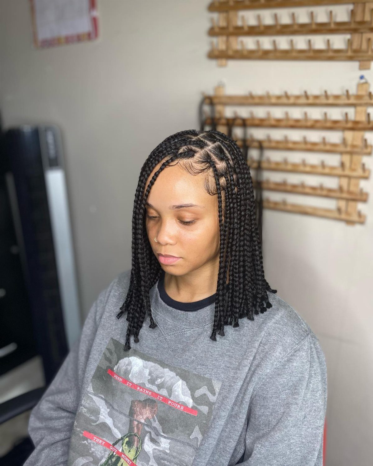 Small black braids fall to the shoulders as a woman looks down