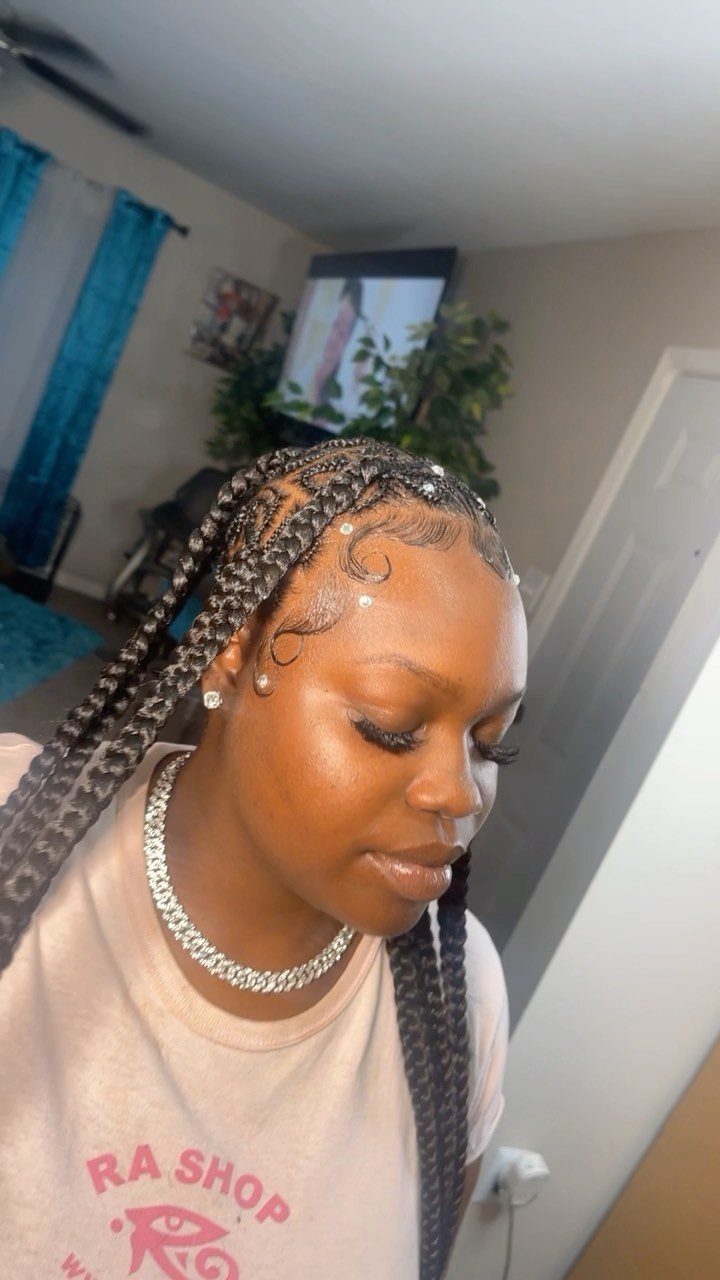 Woman with long black braids and laid edges poses in a room